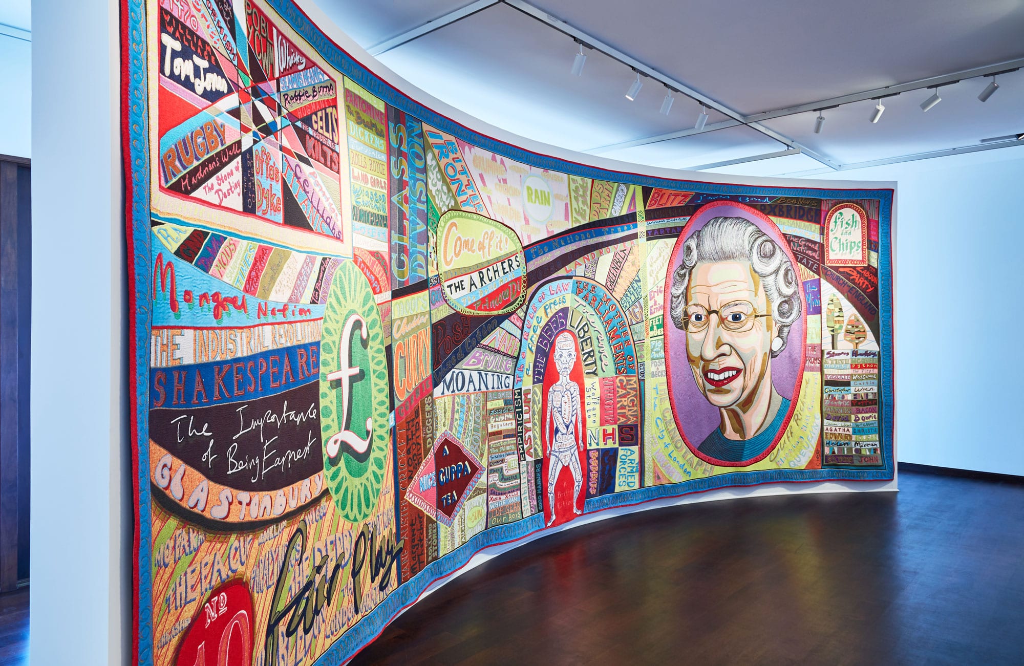 Grayson Perry’s “portrait of Britain to wrap yourself up in” the monumental Comfort Blanket tapestry hung in the West Hall at The Gallery at Windsor.